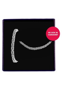 Twee zilveren armbanden tentoongesteld op een zwarte achtergrond: de ene heeft ingewikkelde patronen, de andere een gladde gevlochten ontwerp.