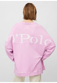 Sudadera rosa de gran tamaño con cuello redondo, que presenta la marca blanca "O’Polo" y "STOCKHOLM '67" impresas en la parte posterior. Textura de tela suave.