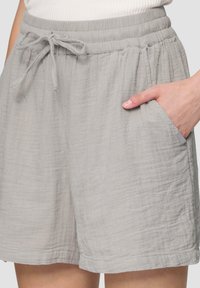 Grijze, lichte shorts met een elastische tailleband, verstelbare trekkoord en zijzakken. Gelaagd stof met een licht gekreukt uiterlijk.