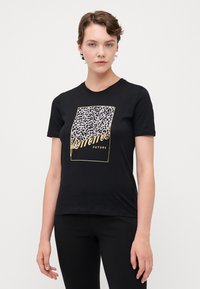 Svart bomull t-skjorte med leopardmønster grafikk rammet i gull, med teksten "femme FUTURE" i en moderne skrifttype.