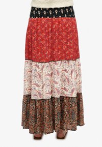 Multikleurige, gelaagde maxi-rok met bloemen- en paisleypatronen. Materialen zijn lichtgewicht stof; de kleuren zijn rood, zwart, roomkleurig en marineblauw.