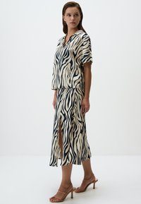 Ensemble de haut à manches courtes et de jupe midi en ivoire avec des rayures zèbres noires. Comprend un col, une fente sur la jupe et un tissu léger.