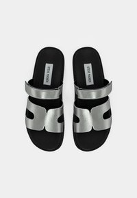 Silver metallic slides with cut-out design, synthetic upper, adjustable strap, and black textured footbed. Brand logo visible on footbed.