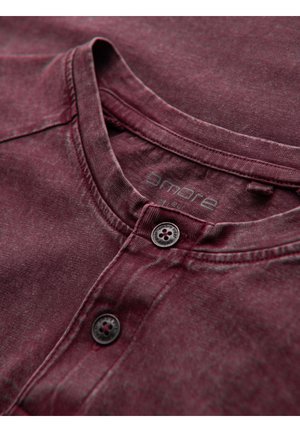 Burgundská bavlněná košile typu henley s texturovaným povrchem, kulatým výstřihem, dvěma černými knoflíky a decentně tištěným logem značky.