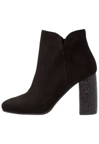 Czarne zamszowe botki za kostkę z ostrym noskiem i teksturowanym czarnym blokowym obcasem. Prosty design z wygiętym wlotem i bez widocznych zapięć.