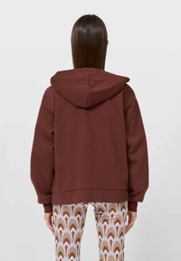 Bordeauxkleurige hoodie met een relaxte pasvorm, geribde manchetten en zoom. Gecombineerd met gemusterde, meerkleurige leggings met golfmotieven.