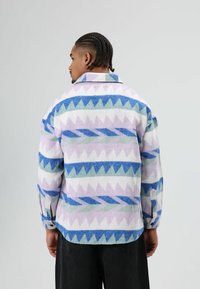 Meerkleurig fleece shirt met geometrische patronen in blauw, groen, paars en wit; kraagmodel met knoopmanchetten en een ontspannen pasvorm.