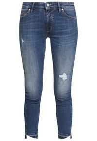 Jeans slim fit de tiro medio en denim azul oscuro con ligeras desgastaciones. Cuenta con cierre de botón, bolsillos y dobladillos deshilachados.