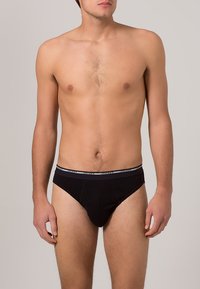 Schwarze Baumwollslips mit taillierter Passform und elastischem Bündchen, das ein graues Jockey-Logo trägt. Glatte Textur und minimalistischer Stil.