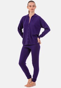 Lila gestricktes Loungewear-Set mit einem Hemd zum Knöpfen und eng anliegenden Hosen, ausgestattet mit einem klassischen Kragen und einer weichen Textur.