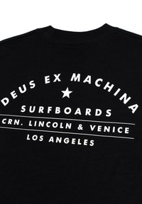 Black fabric T-shirt featuring bold white text: "DEUS EX MACHINA SURFBOARDS CRN. LINCOLN & VENICE LOS ANGELES" with a star accent.