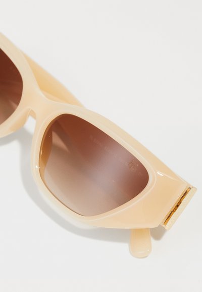 Peach-colored sunglasses with a chunky design and gradient brown lenses. Features a glossy finish and subtle gold accents on the temples.