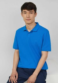 Blaues Poloshirt aus Baumwolle mit klassischem Kragen und kurzen Ärmeln. Verfügt über eine Zwei-Knopf-Leiste und ein dezentes Logo auf der Brust.