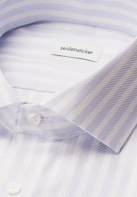 Jasnoniebieska koszula w białe paski z kołnierzykiem, z metką Seidensticker, prezentująca fakturowany materiał i detale guzików.