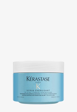 Kérastase Peeling in einem zylindrischen hellblauen Kunststofftopf mit einem weißen Deckel. Das Etikett auf der Vorderseite zeigt schwarze Schrift und Details über das Produkt im Inneren.