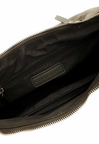 Canvas pouch in dark green, featuring a zip closure, interior zip pocket, and embossed label. Soft texture with a simple design.