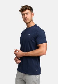 Granatowa koszulka bawełniana z krótkim rękawem, okrągłym dekoltem i subtelnym logo na piersi. Gładka faktura i luźny krój.