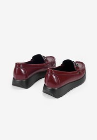 Mocasines de cuero burdeos con parte superior texturizada, suela sintética negra, laterales elásticos y costuras decorativas. Punta redonda y tacón bajo.