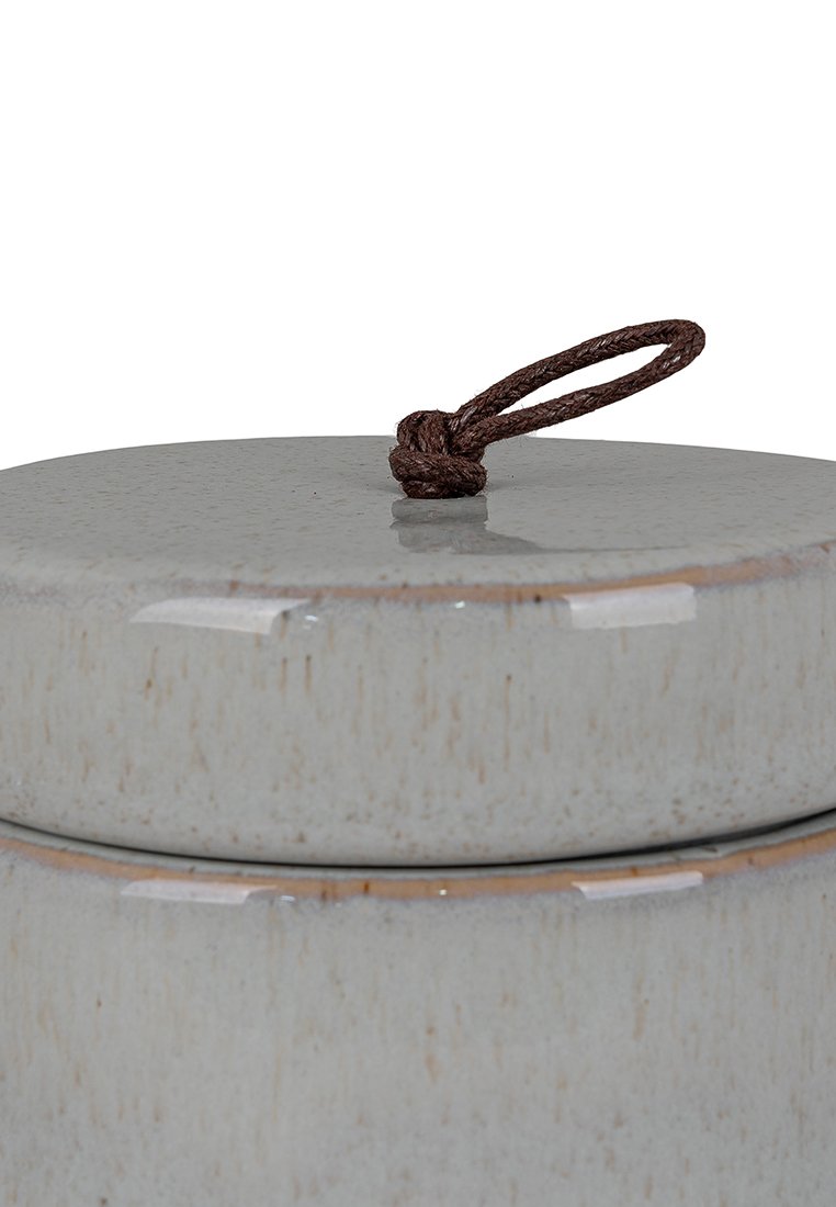 Ceramiczny pojemnik do przechowywania o gładkim, jasnoszarym wykończeniu, z okrągłą pokrywą i brązowym sznurkowym uchwytem. Widać subtelne detale tekstury.