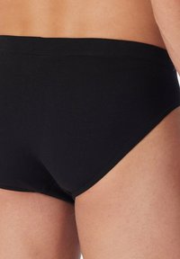 Slip da uomo in cotone nero con una texture liscia, dotati di un ampio elastico in vita e un design semplice. Senza motivi o dettagli visibili.