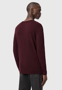 Maglione in maglia bordeaux con maniche lunghe, scollatura a girocollo e vestibilità rilassata. Presenta una finitura testurizzata e orli e polsini a coste.