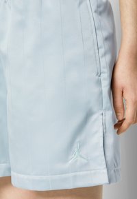 Short bleu clair avec un motif subtil à rayures verticales, une poche latérale, une petite fente près de l'ourlet et un logo Jumpman brodé en bleu clair.