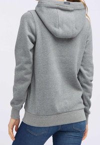 Sudadera gris con capucha, textura suave y puños y dobladillo de canalé, combinada con jeans azules. Muestra la vista trasera, destacando los detalles del diseño.