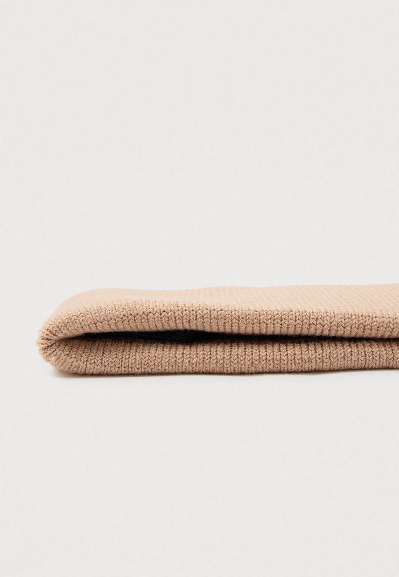 Gehaakt, beige stof strak opgerold, met een gladde textuur en een consistente ribbelpatroon langs het oppervlak. Geen aanvullende details zichtbaar.