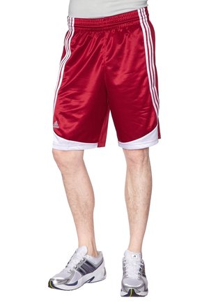 Mann trägt rote und weiße Adidas-Sportshorts und weiße Laufschuhe, steht vor einem weißen Hintergrund.