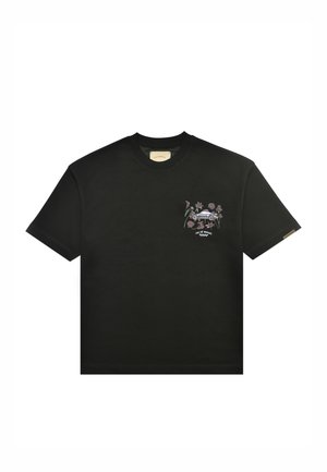 T-shirt nera a maniche corte con una piccola grafica floreale e una macchina sul petto sinistro, con il testo "Pas De Monaco" sotto.