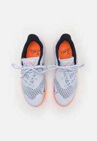 Scarpe da ginnastica bianche con tomaia in rete, accenti blu navy e solette arancioni brillanti. Presentano lacci piatti e un design a motivi sottili sui lati.
