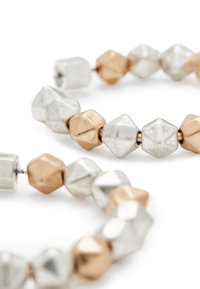 Beaded bracelet featuring metallic hexagonal and cubic beads in silver and gold tones, with a smooth texture and alternating shapes.