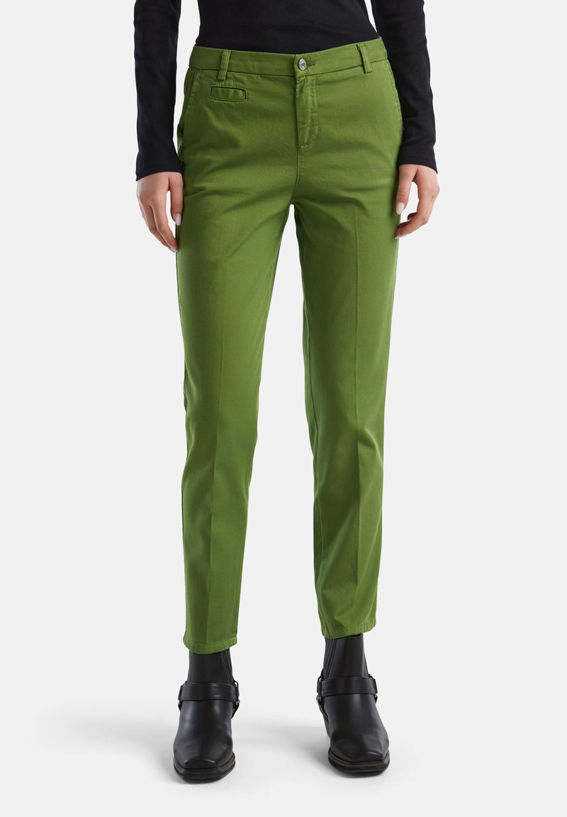 Pantalons en coton verts avec une coupe slim, dotés d'une fermeture à bouton, de poches latérales et d'une texture lisse, associés à des bottines noires.