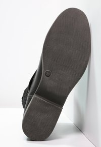Suela de zapato negra con goma texturizada, con un diseño plano y ligeras ranuras para tracción, marcada con la talla 39. Superficie lisa y duradera.