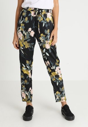 Pantalons noirs à fleurs avec une texture brillante, dotés d'une taille à cordon de serrage et de motifs floraux vibrants en rose, jaune et vert.