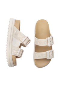 Sandales blanches avec deux brides ajustables présentant un matériel texturé. Semelle intérieure douce et semelle en caoutchouc avec un motif ondulé pour une meilleure adhérence.