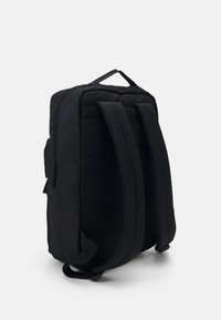Black fabric backpack with padded mesh straps, flat zippered exterior pocket, and a sleek, minimalist design. Textured back for comfort.