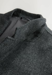 Dunkelgrauer Wollmischungs-Mantel aus strukturiertem Stoff, mit einem Stehkragen und einem eleganten, minimalistischen Design. Keine sichtbaren Beschläge oder Akzente.