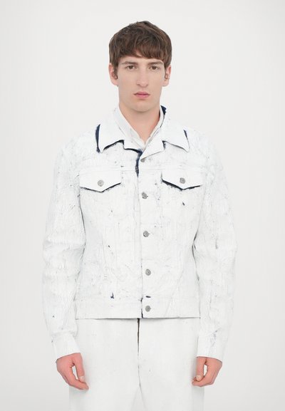 Chaqueta de mezclilla blanca con un sutil patrón texturizado, que presenta botones plateados, bolsillos con solapa y un acento azul oscuro en el cuello.