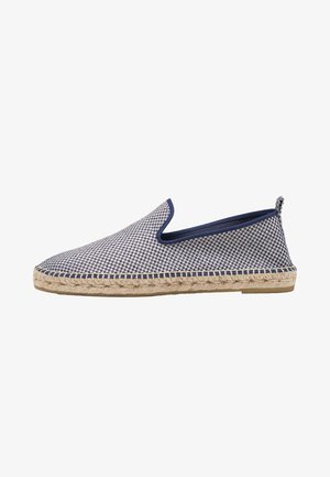 Zapato tipo slip-on de patrón azul y blanco con suela de cuerda de yute y parte superior de tela texturizada. Presenta una puntera redonda y un talón bajo.
