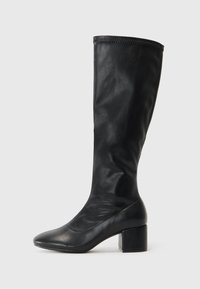 Bottes noires montantes en cuir lisse. Elles présentent un talon carré et une silhouette élancée avec une tige simple et des détails cousus en haut.