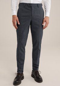 Skräddarsydda mörkblå byxor med ett subtilt rutmönster, rak passform, sidofickor och en mjuk textur, tillsammans med svarta skor.