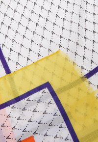 Foulard in seta con sfondo bianco e un motivo ripetuto di 'A' neri, accentuato da forme geometriche vibranti gialle e viola e bordi sfrangiati.