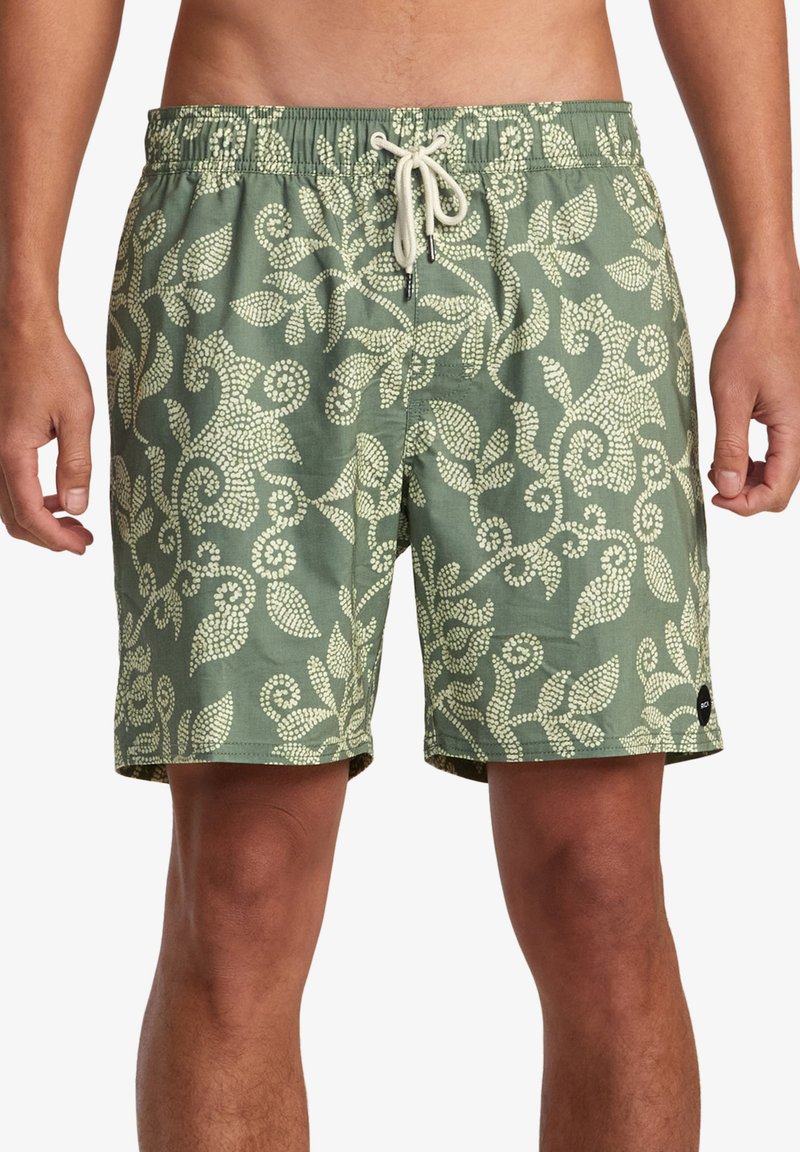 Pantaloni da bagno verdi con un motivo floreale bianco, vita elastica, chiusura con cordoncino e tasche laterali. Il tessuto ha una texture liscia.