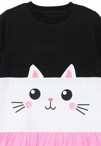 Top negro con un medio blanco que presenta un diseño de cara de gato. Los acentos en rosa incluyen orejas y una falda con volantes. Material de algodón suave en todo.