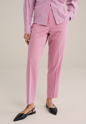 Pink tailored trousers with a straight cut, featuring a smooth fabric finish. Paired with black pointed slingback shoes.