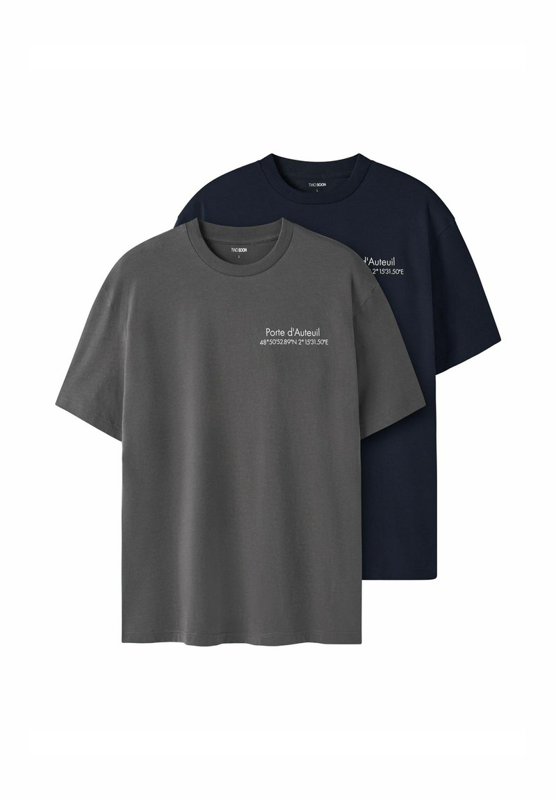 To kortærmede t-shirts, en i mørkegrå og en i navy. Fremstillet i bomuld med rund hals og et trykt motiv på brystet.