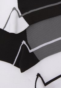 Tejido de punto en negro, blanco y gris con patrones geométricos y rayas en contraste. Textura suave con acabado liso.