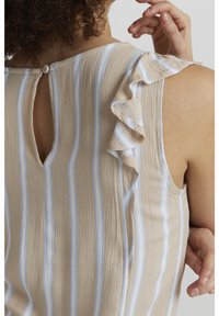 Top a righe beige con linee azzurre chiare, dotato di spalla arricciata e chiusura a bottoni sul retro, realizzato in un morbido tessuto testurizzato.