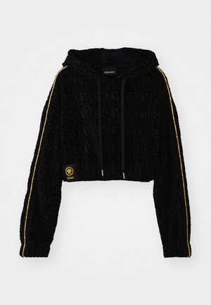 Sudadera negra recortada con el logo en relieve de 'Versace', rayas amarillas a lo largo de las mangas y detalles en dorado. Textura suave de terciopelo.